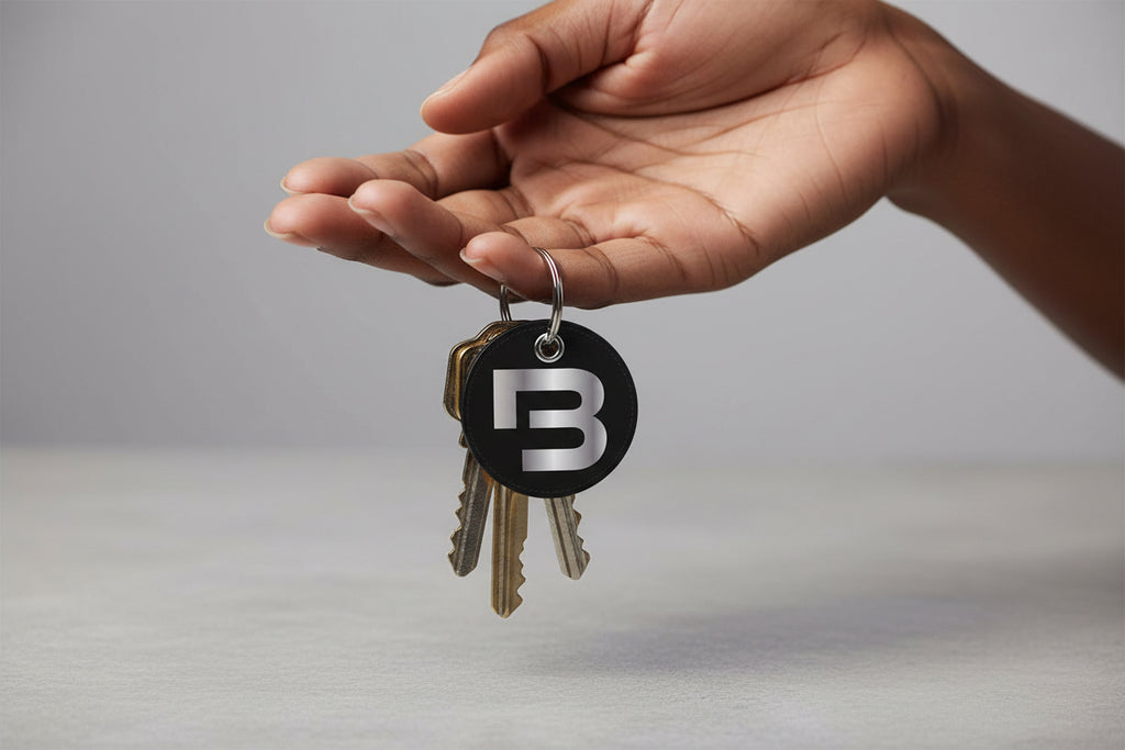 Black round keychain with silver logo on a white background